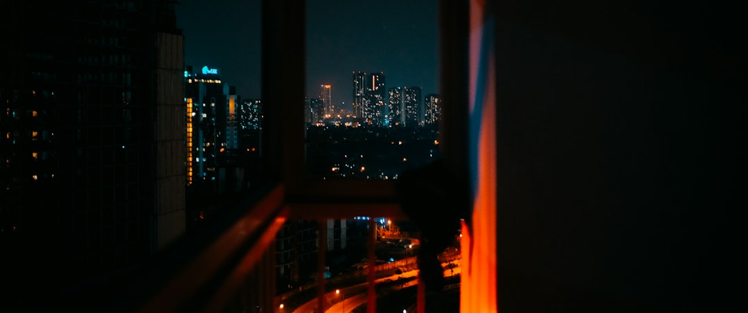 A city glowing at night as seen through a dark window