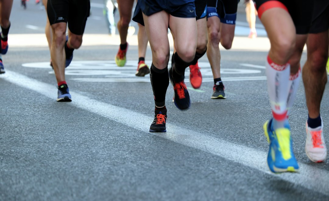 A pack of runners' legs crossing a painted line on the road