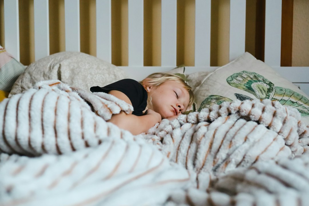 Young child sleeping soundly under a striped blanket