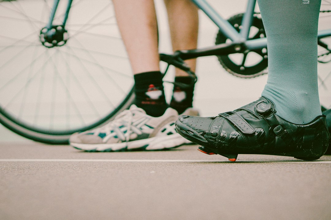 A stiff cycling shoe beside a softer sneaker, the pedal choice that changes how a recumbent feels
