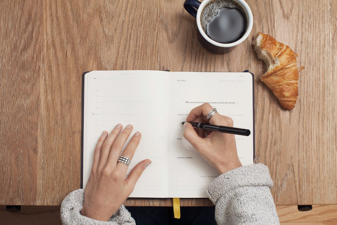 Hands writing a morning journal beside coffee