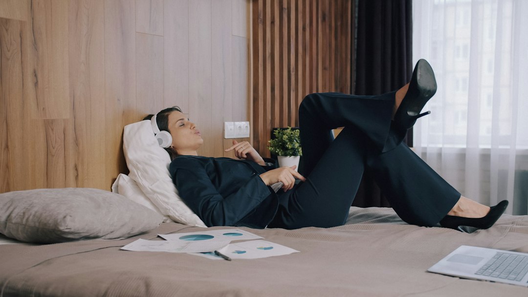Woman relaxing on a bed wearing over-ear headphones in a bright bedroom