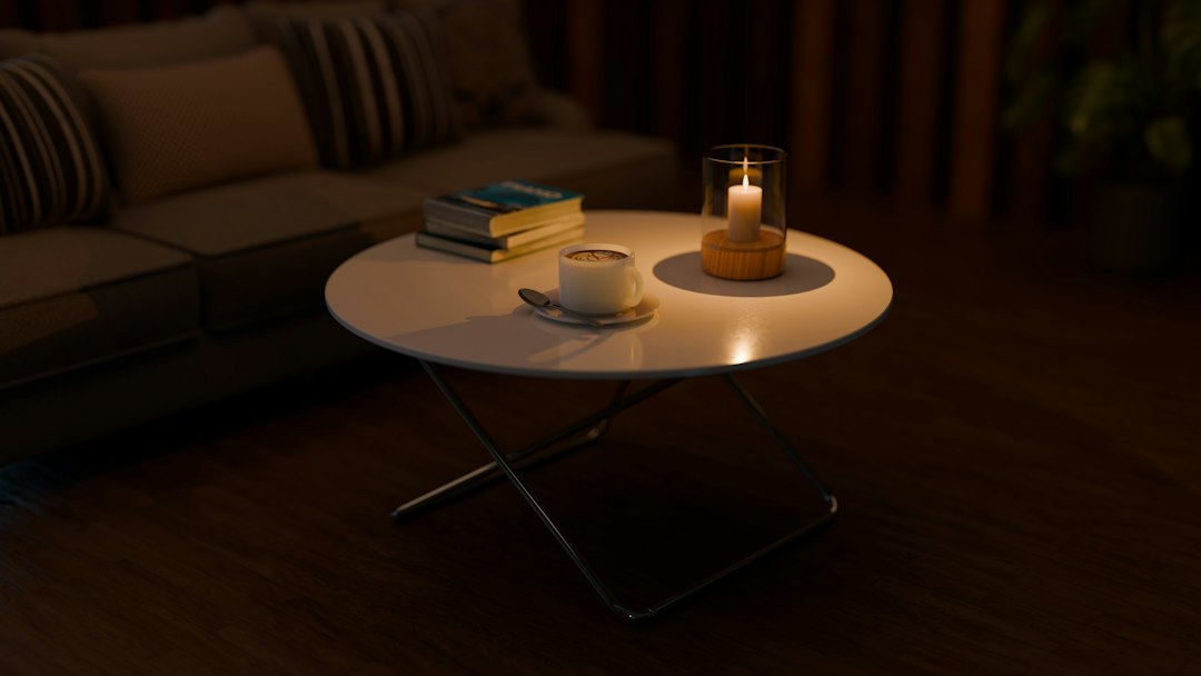 A lit candle beside a stack of books on a living room table