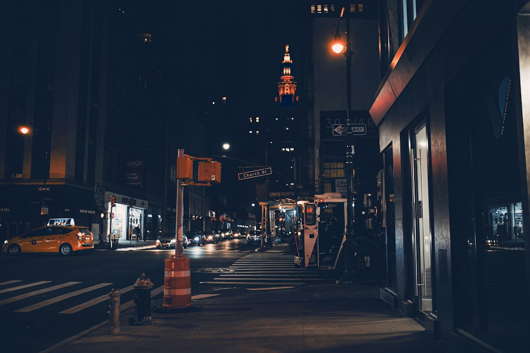 A wet city street at night with traffic and glowing skyscrapers in the background