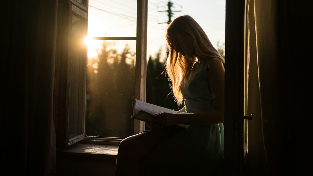 Woman reading by a window at the end of the day, the quiet that a recovery mat is supposed to protect