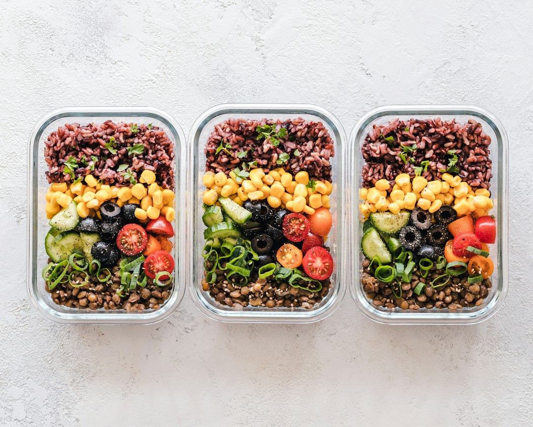Three glass meal prep containers filled with grains, vegetables, and lentils