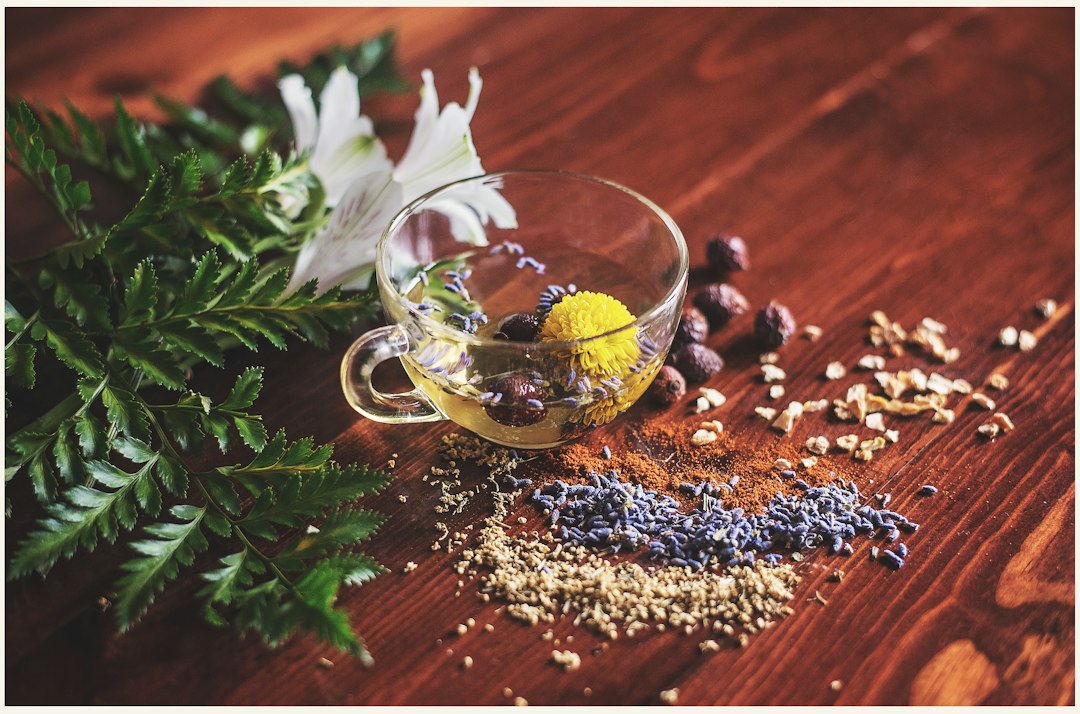 A glass cup of herbal tea with dried flowers on a wooden table