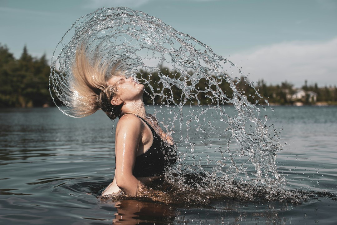 Woman emerging from a lake with a splash of cool water