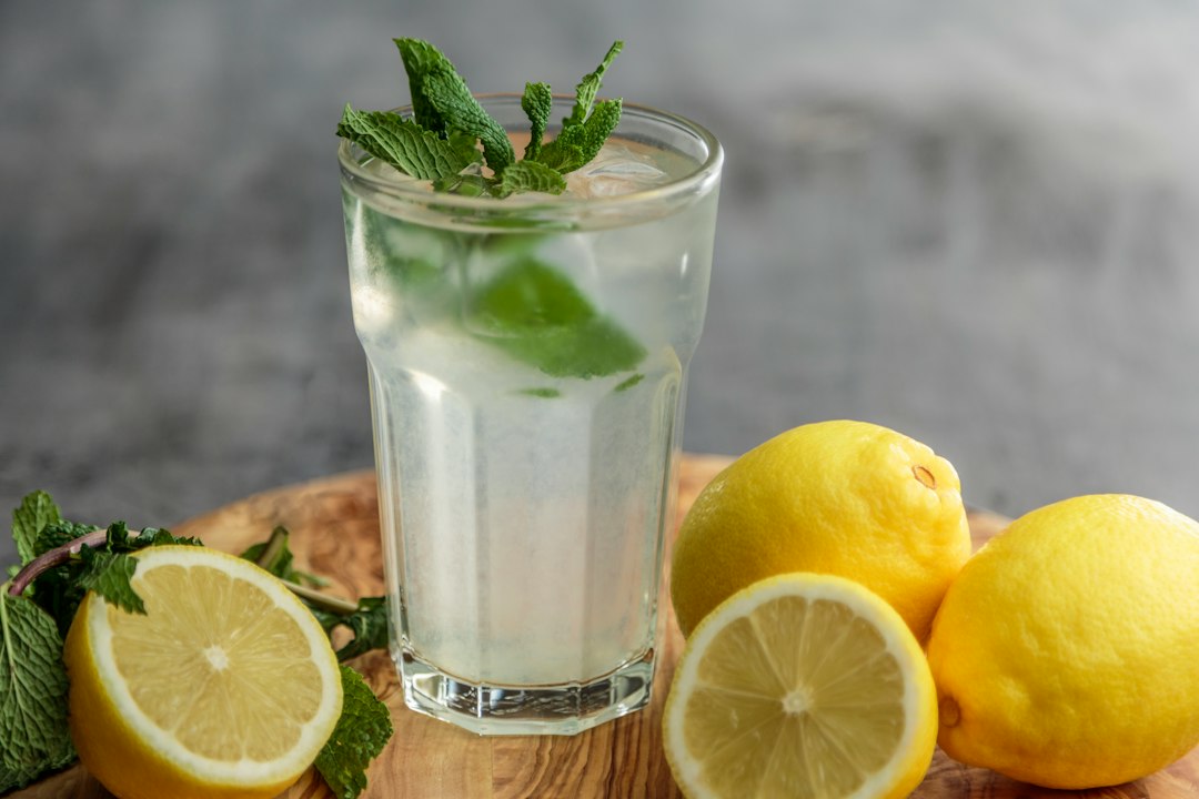 A tall glass of lemon mint iced drink with fresh lemons