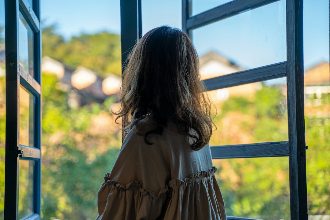 woman standing at a bright sunlit window in the morning