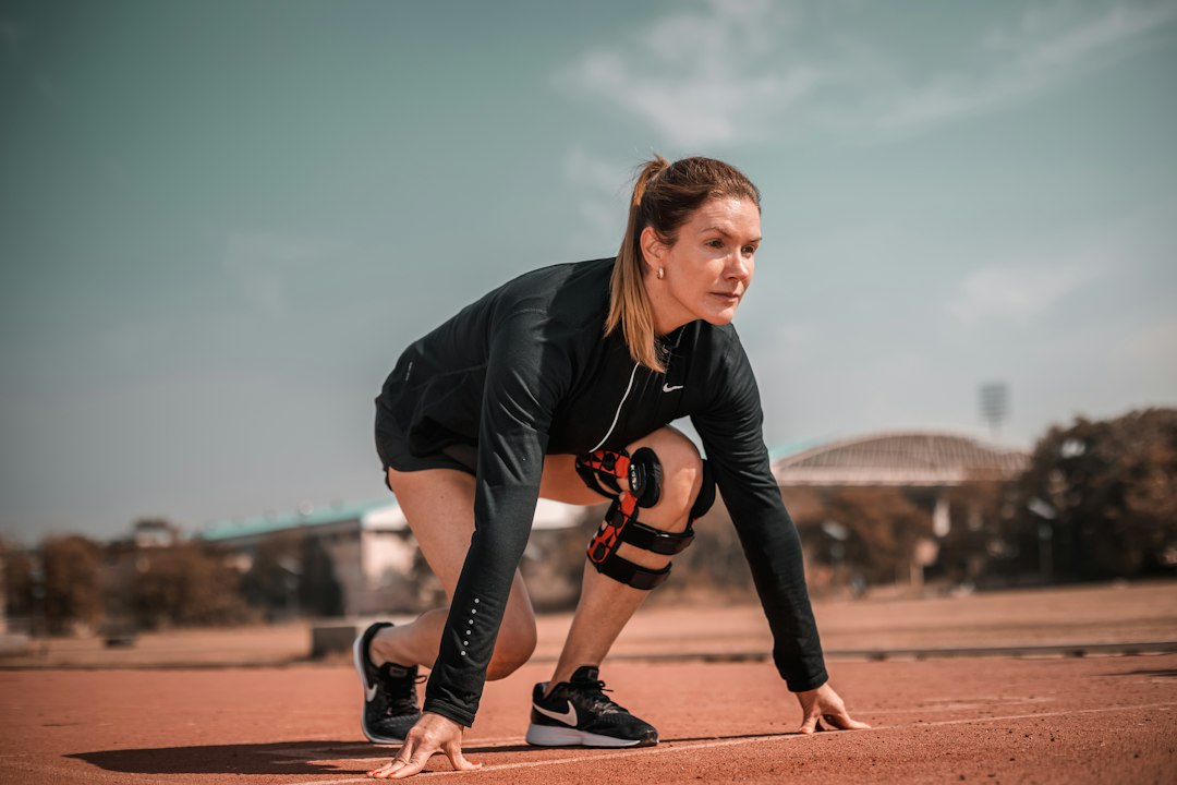 A runner in starting blocks wearing a hinged knee brace