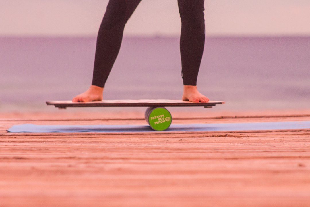 Bare feet balancing on a wooden board resting on a foam roller