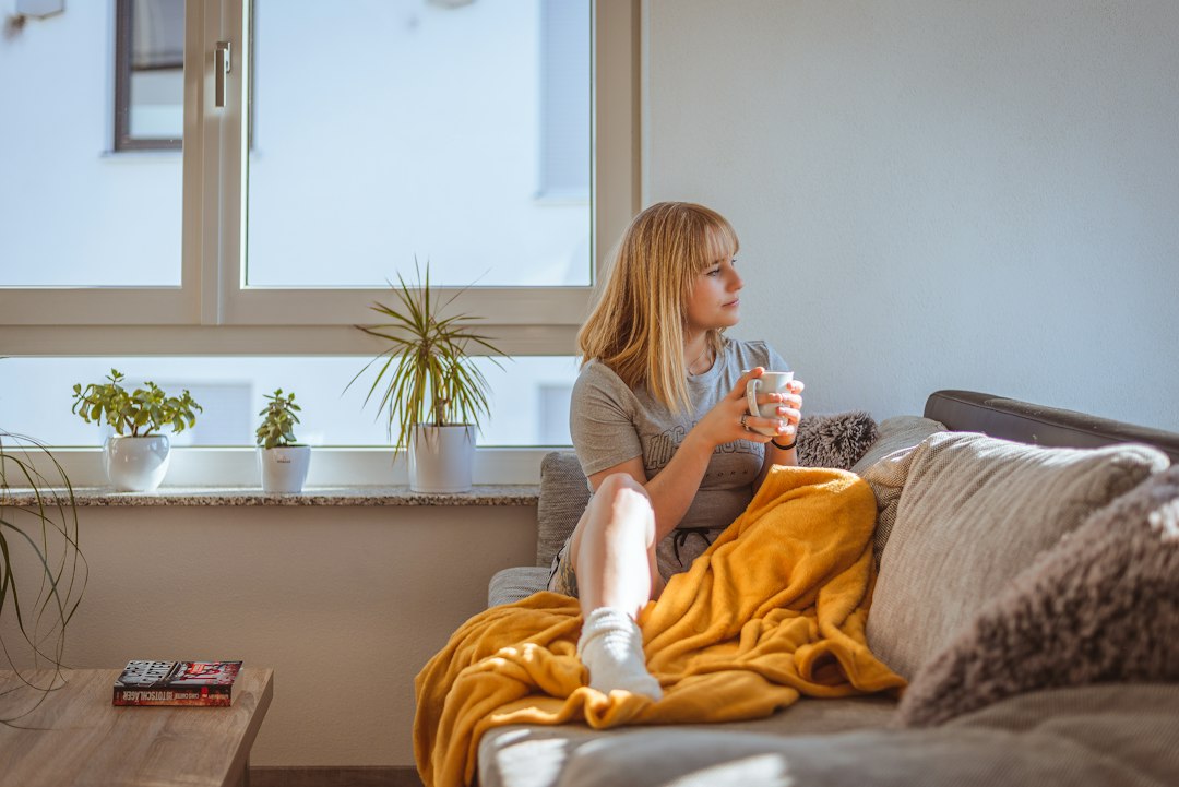 A woman resting on the couch under a blanket