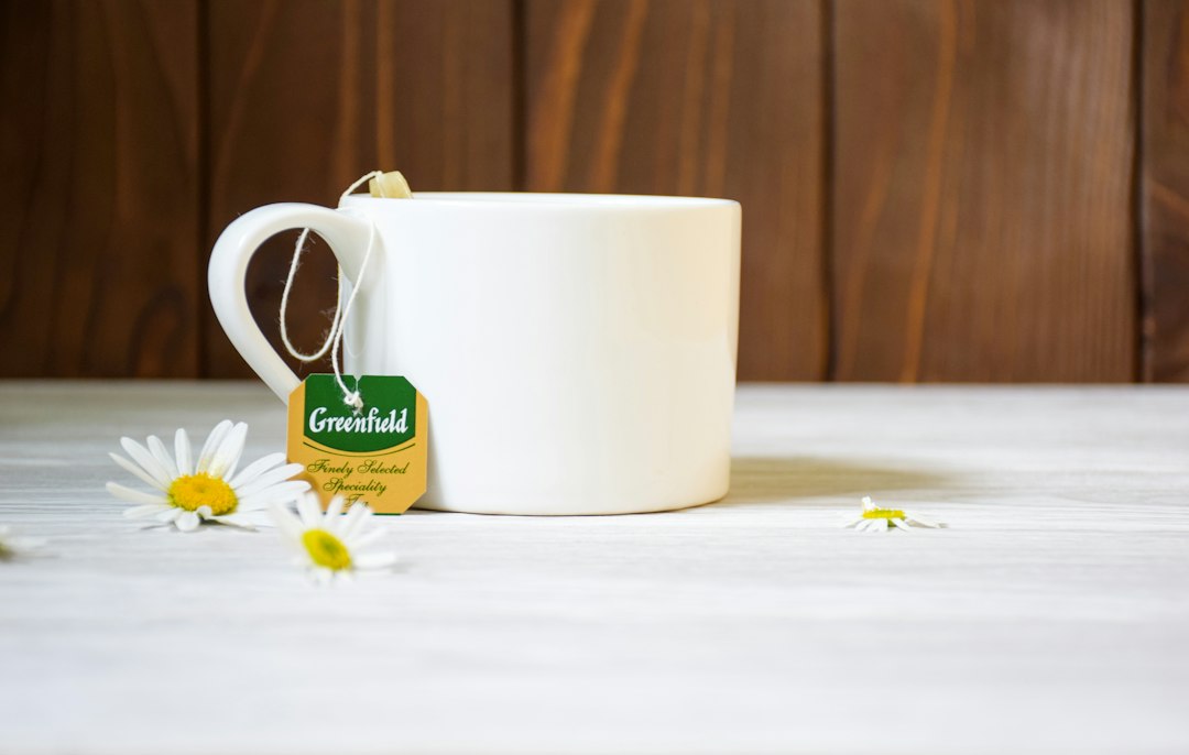 A mug of herbal tea beside fresh chamomile flowers in warm evening light