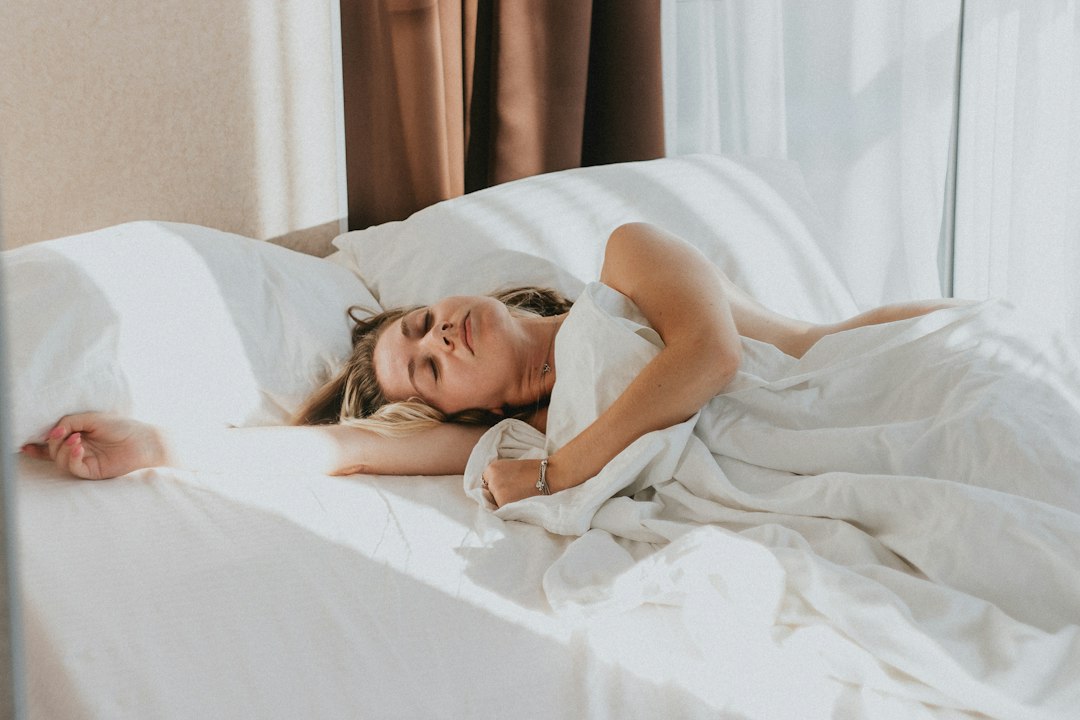 Woman sleeping peacefully in a bright bed with soft morning light