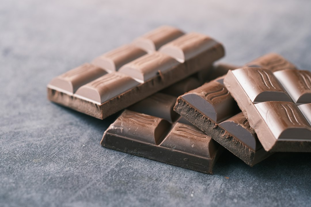Broken pieces of dark chocolate bar on a gray stone surface