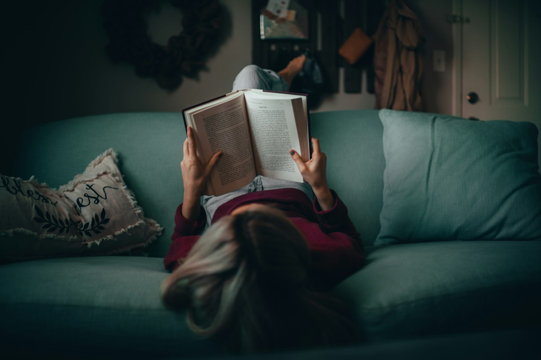 A person reading a book on a couch in a cozy evening living room