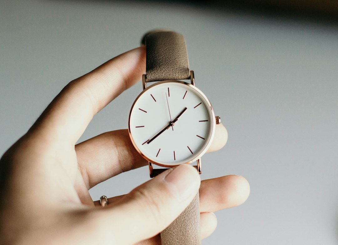 Hand holding a minimalist watch by its strap