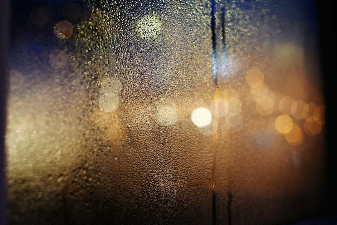 Condensation droplets covering a cold window at night